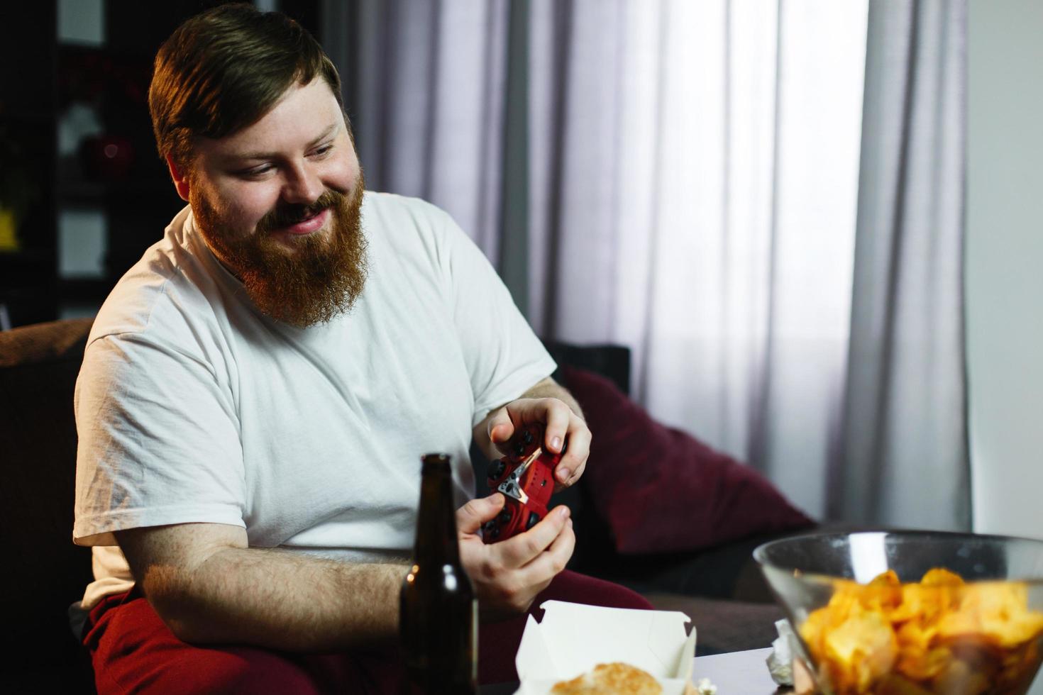 glücklicher dicker Mann im schmutzigen Hemd spielt Videospiele foto