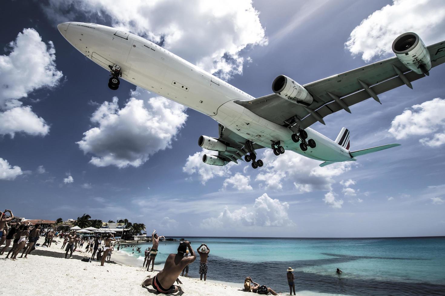 st. Martin, 2013-Touristen drängen sich am Strand von Maho, während sich niedrig fliegende Flugzeuge der Landebahn über der Küste nähern foto