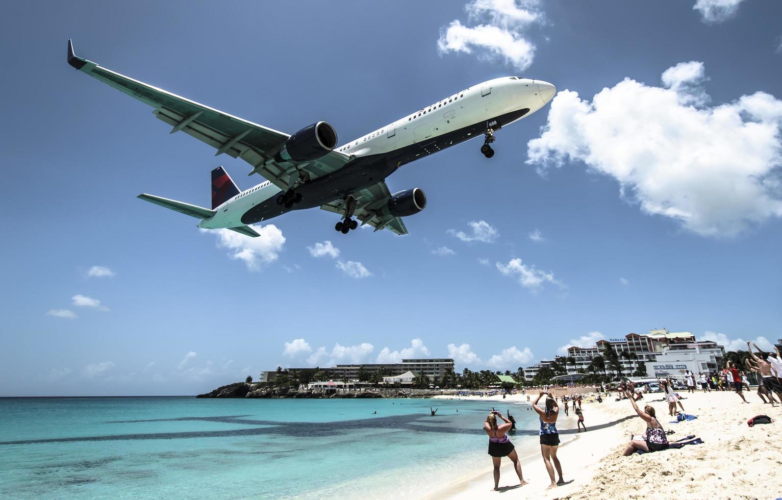 st. Martin, 2013-Touristen drängen sich am Strand von Maho, während sich niedrig fliegende Flugzeuge der Landebahn über der Küste nähern foto