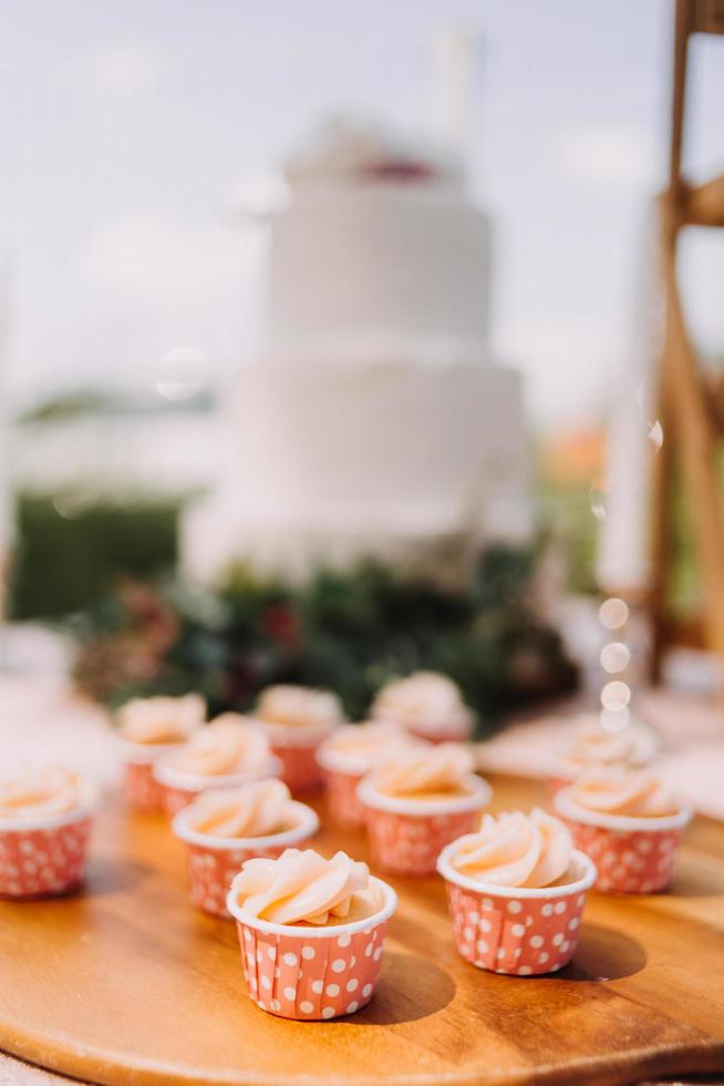 Gourmet-Cupcakes mit weißem Buttercreme-Zuckerguss und Streuseln auf Holzhintergrund foto