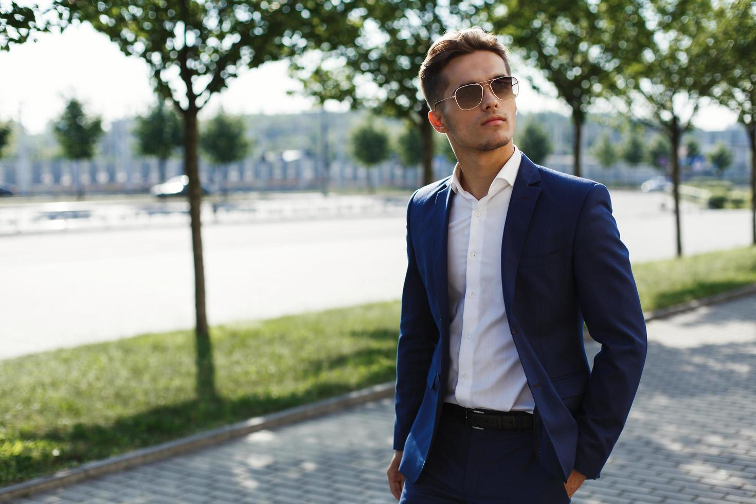 gutaussehender Mann in einem Business-Anzug geht die Straße entlang foto