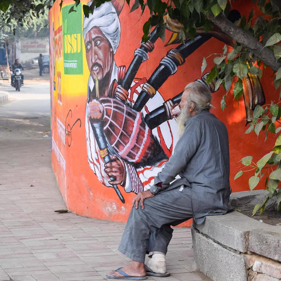 neu delhi, indien - 25. dezember 2021 - alter armer mann trinkt tee während der wintersaison in der alten straße von delhi, delhi straßenfotografie foto