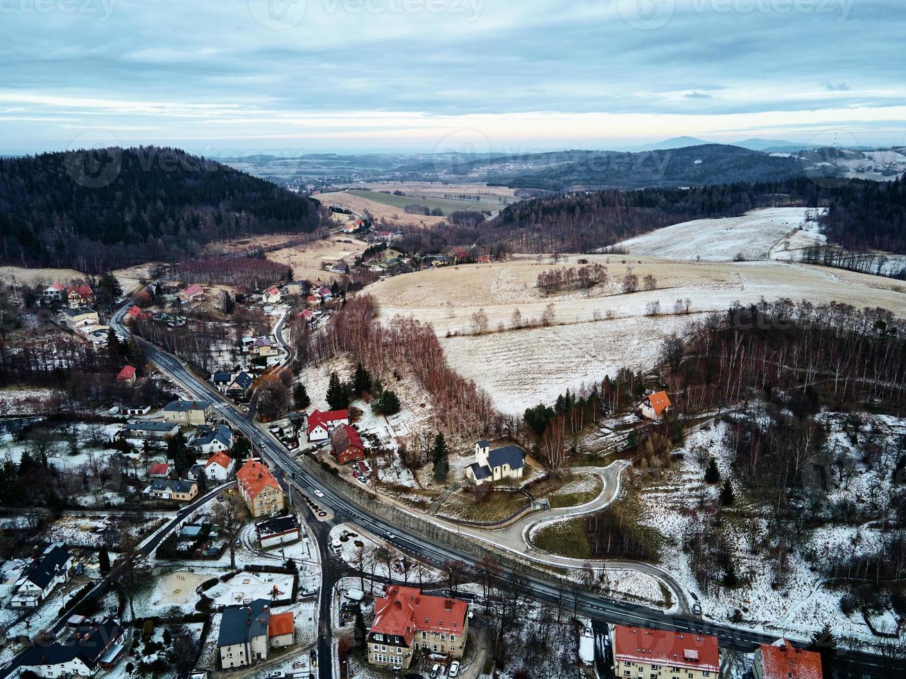 Winterlandschaft mit Dorf in der Nähe von Bergen foto