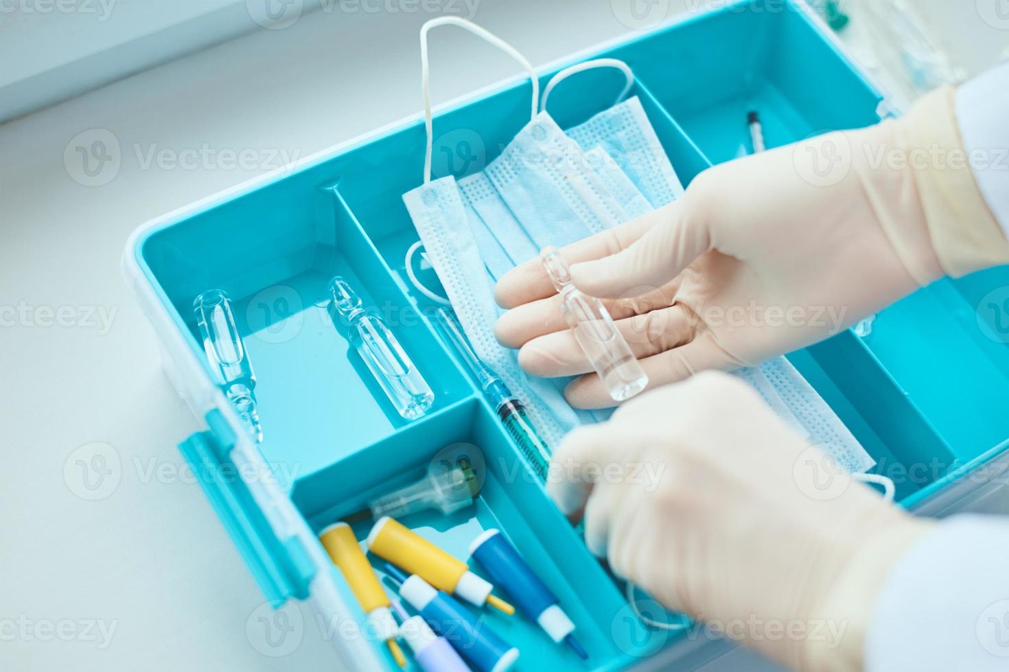 hände in medizinischen handschuhen nehmen spritze aus medikamentenbox foto