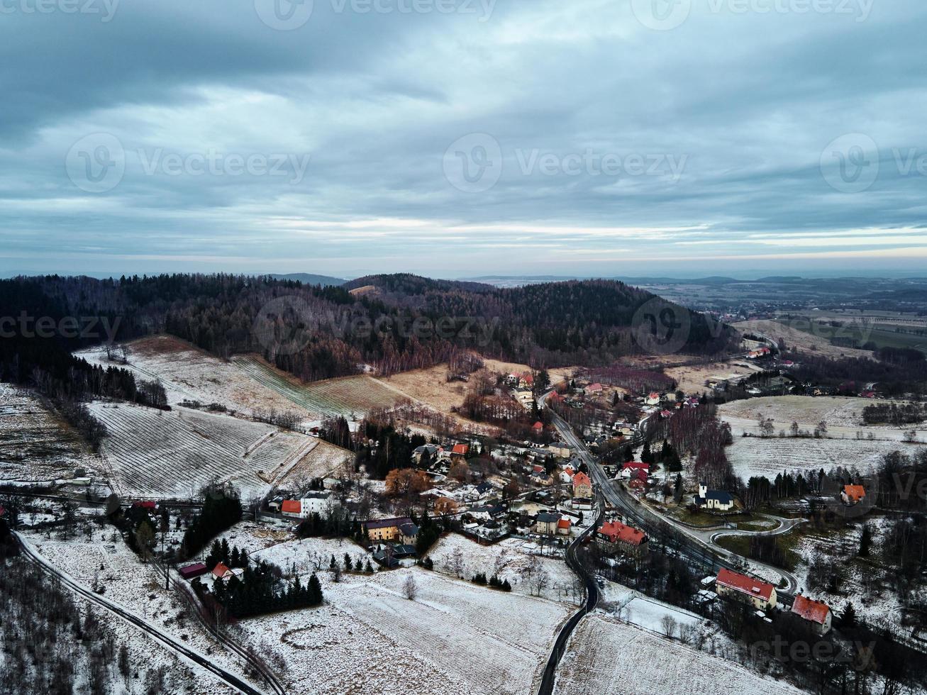 Winterlandschaft mit Dorf in der Nähe von Bergen foto