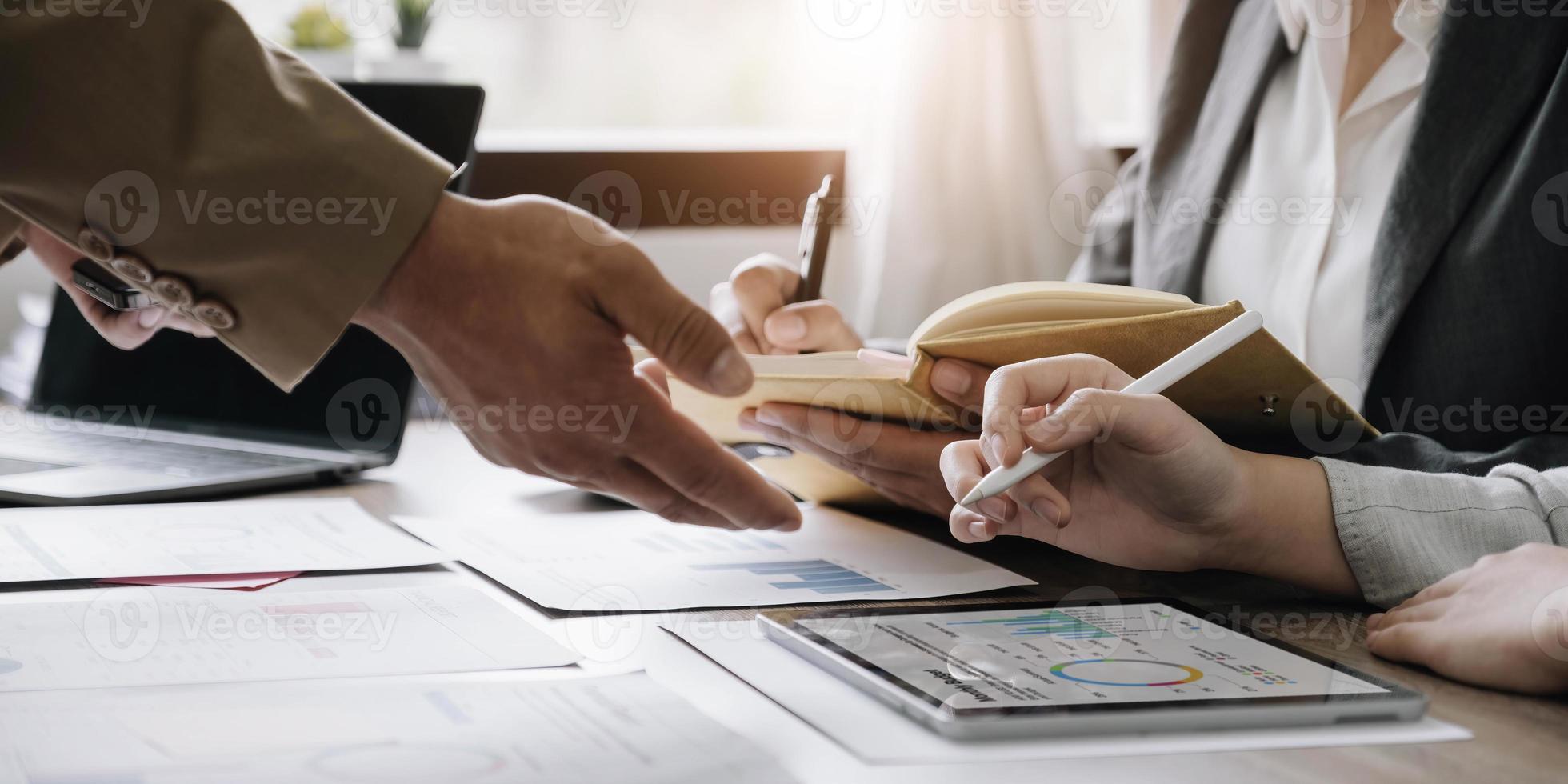 geschäftsleute treffen sich mit laptop-computer, rechner, notizbuch, börsendiagrammpapier für analysepläne, um die qualität im nächsten monat zu verbessern. Konferenzdiskussion Unternehmenskonzept foto