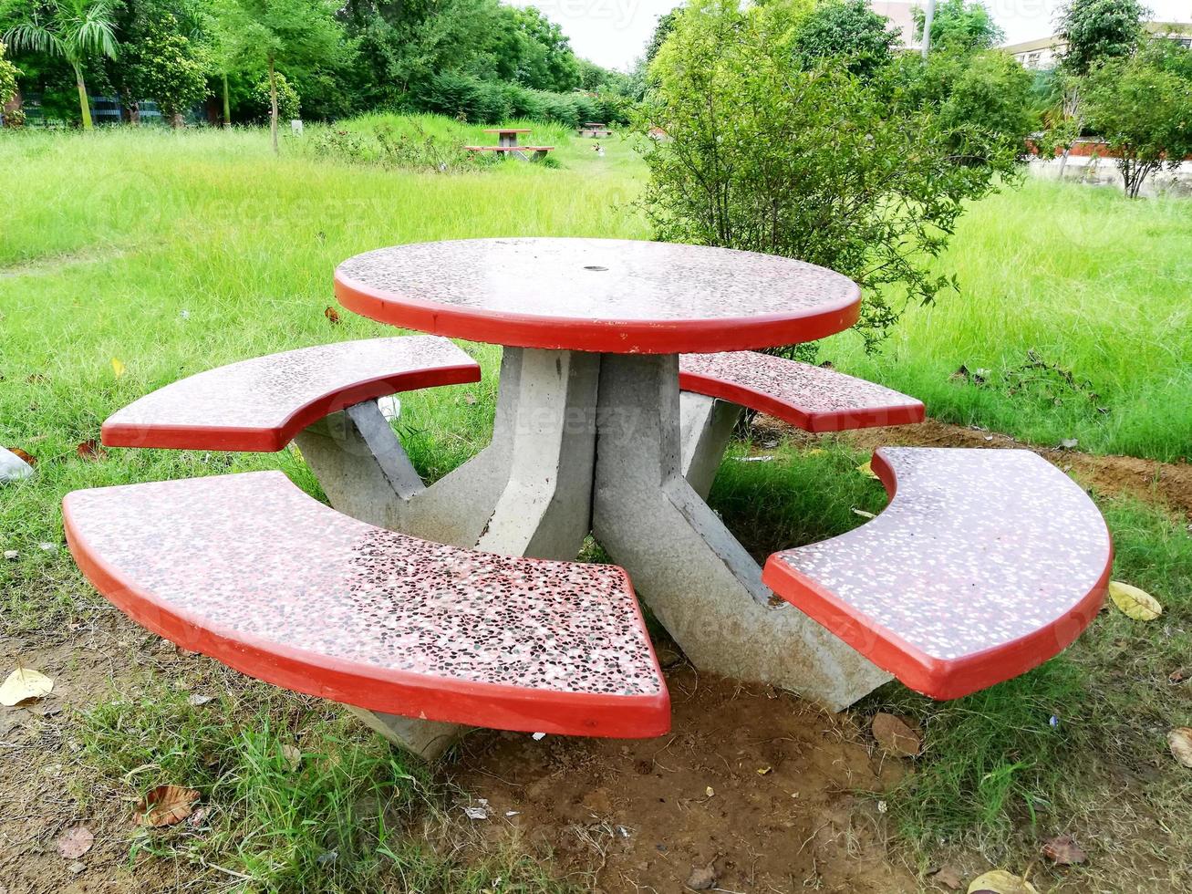 Set aus vier Stühlen und einem Tisch aus Zement in Orangetönen. auf dem Rasen im Garten aufgestellt foto