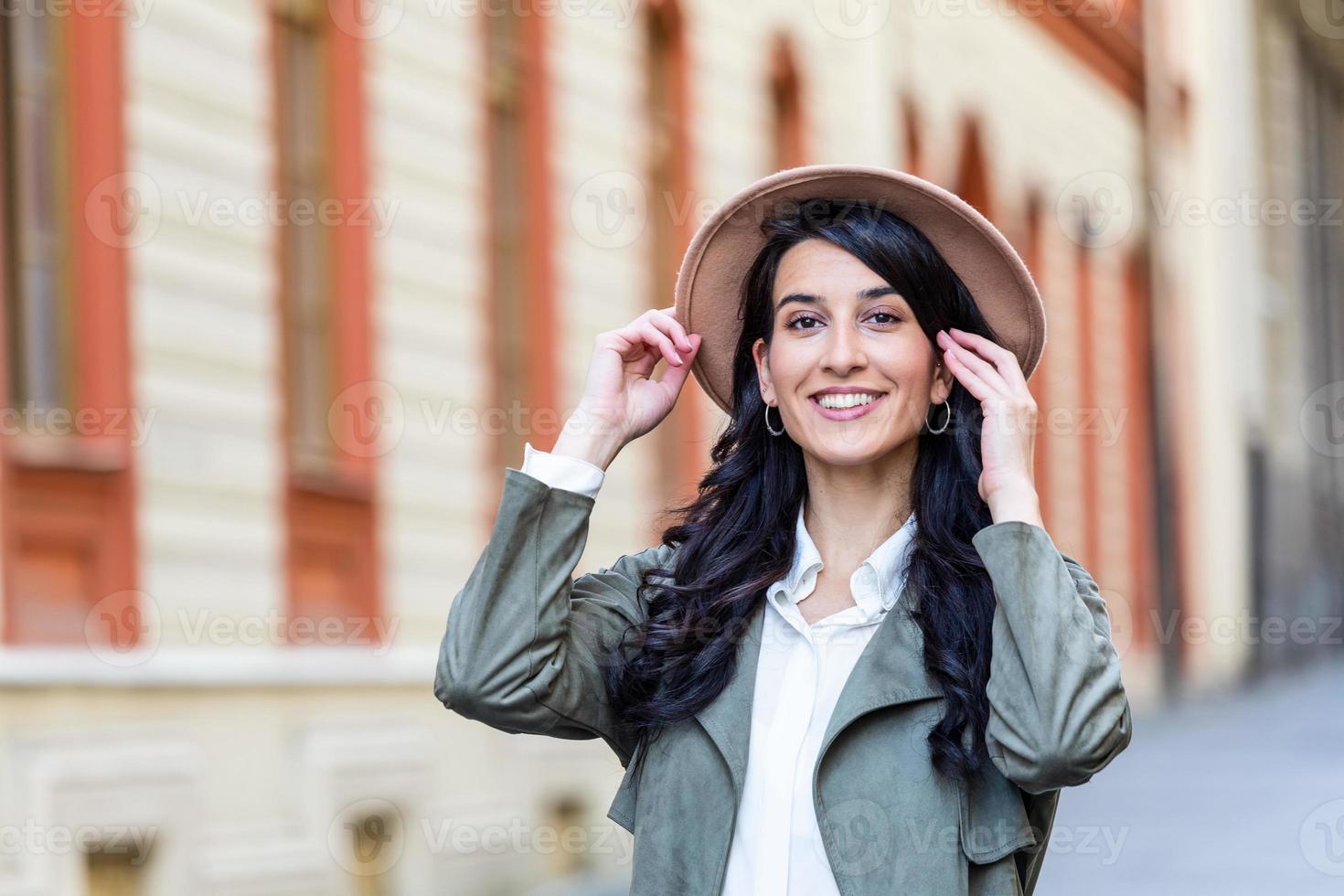 Außenporträt einer jungen, schönen, modischen, glücklichen Dame, die auf einer Straße der Altstadt posiert. Modell mit Hut. Mädchen, das aufschaut. weibliche Mode. urbaner Lebensstil. Platz für Text kopieren foto