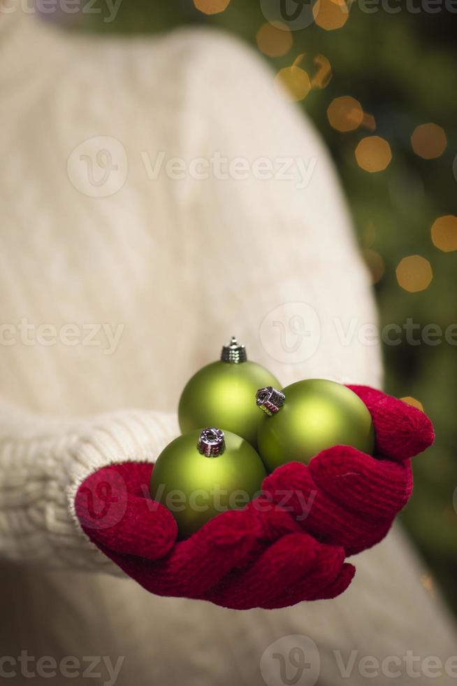 Frau trägt saisonale rote Fäustlinge mit grünen Weihnachtsschmuck foto