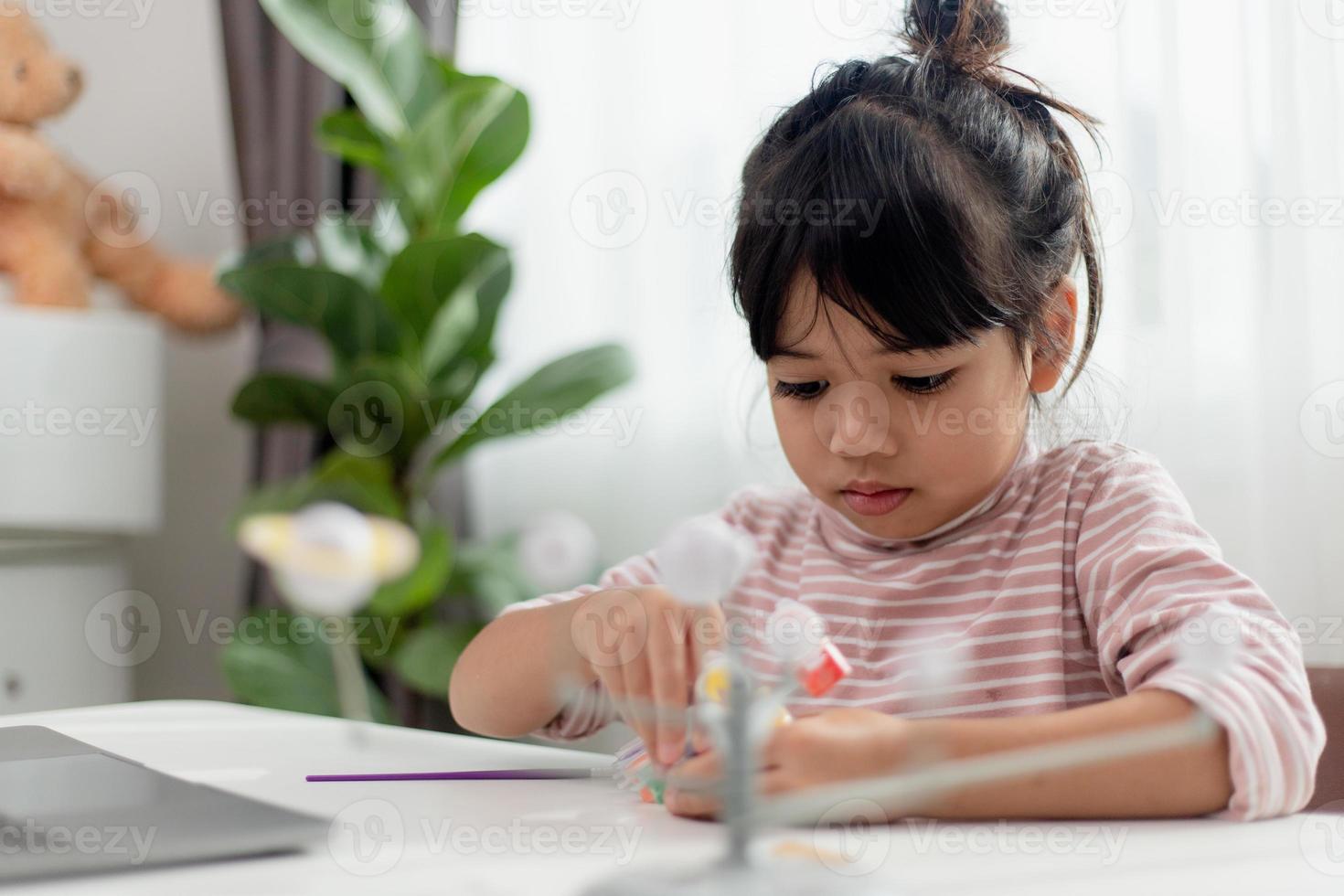 Asiatisches kleines Mädchen studiert das Sonnensystem im Erdkundeunterricht. Blick auf das maßstabsgetreue Modell der Planeten foto