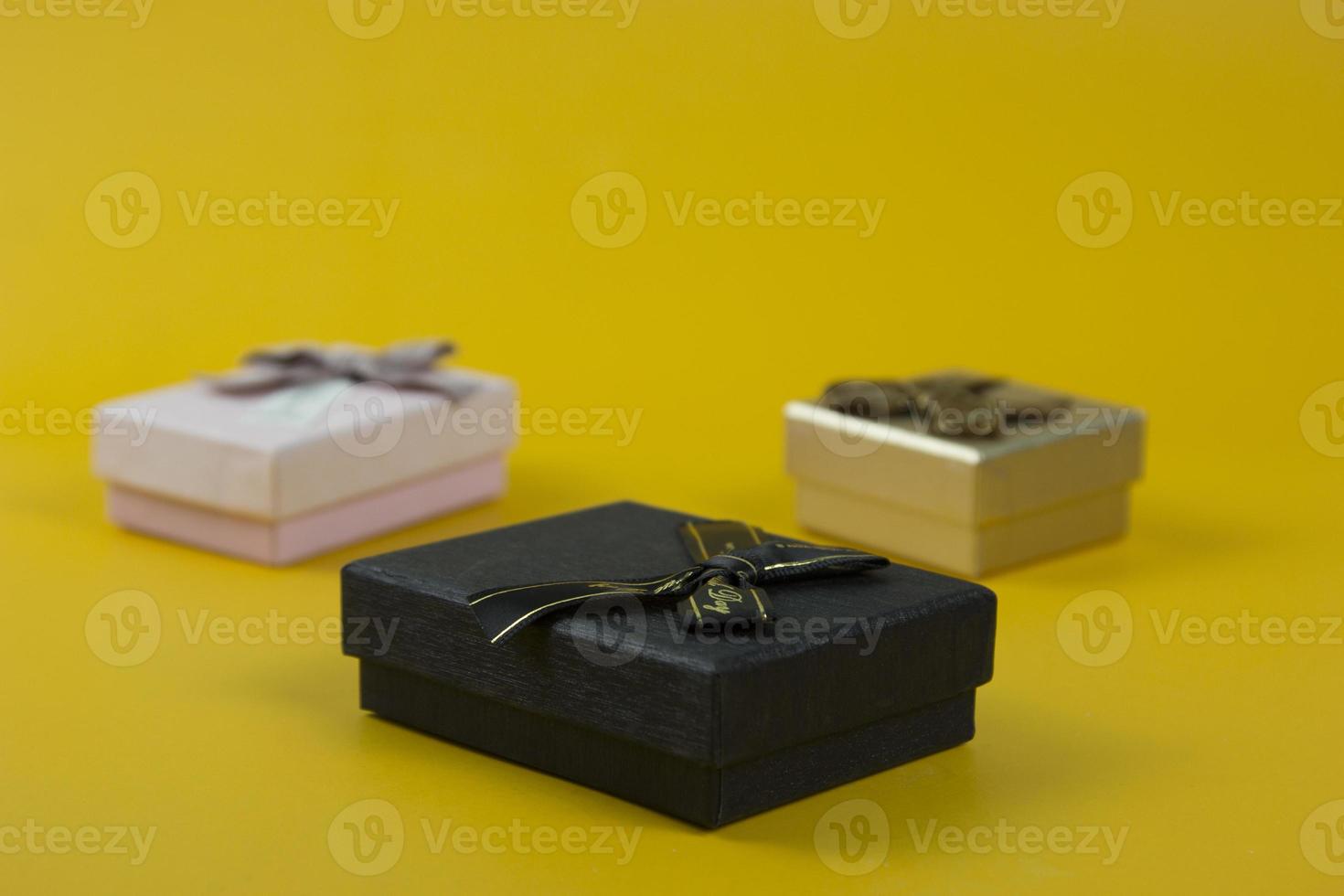 schöne geschenkboxen schwarz, rosa und goldfarbe und konfetti auf gelbem hintergrund. verwendet in geburtstagsvorlage von bannern, postern, broschürendesigns. foto