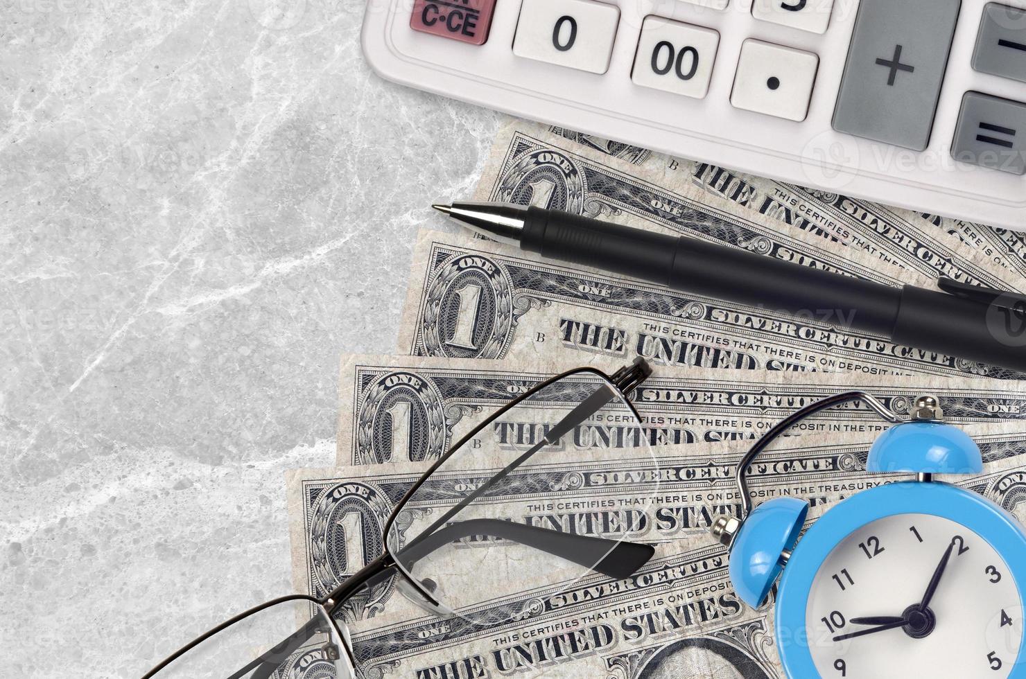 1 US-Dollar-Scheine und Taschenrechner mit Brille und Stift. Konzept für Geschäftsdarlehen oder Steuerzahlungssaison. Zeit, Steuern zu zahlen foto