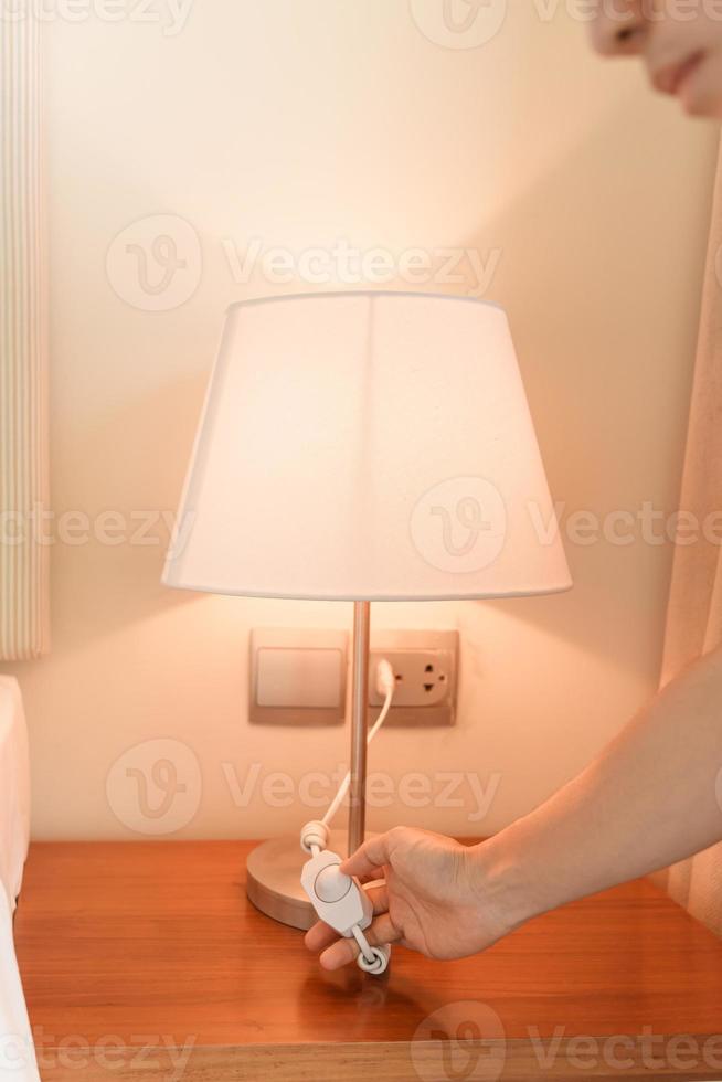 Frauenhand, die die minimale Lampe im modernen Schlafzimmer ein- oder ausschaltet. Apartment-Wohnkonzept foto