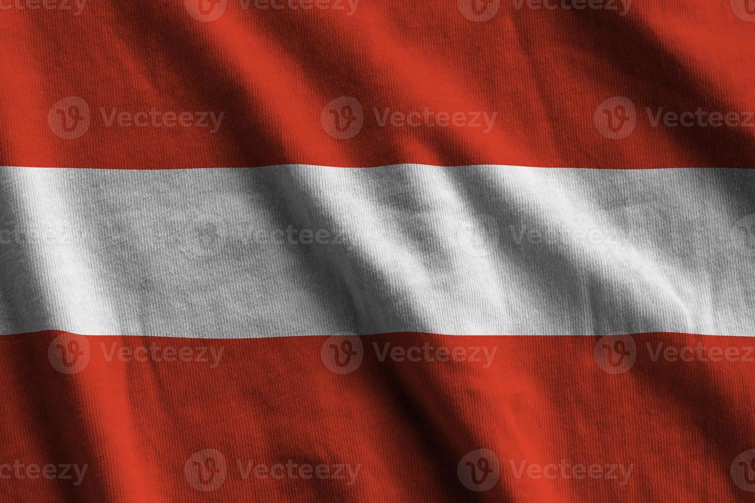 österreichische flagge mit großen falten, die dicht unter dem studiolicht im innenbereich wehen. die offiziellen symbole und farben im banner foto