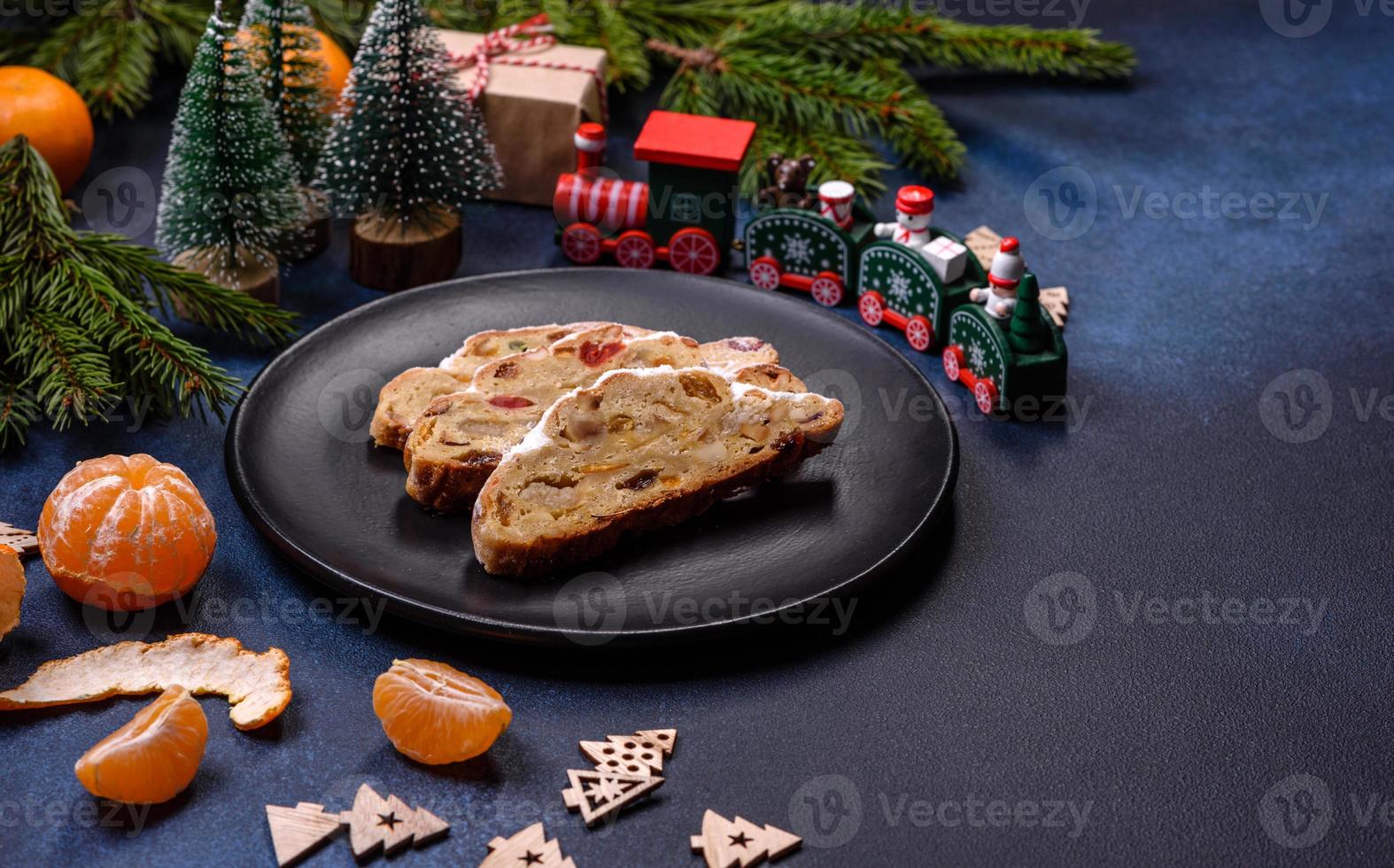 köstlicher festlicher neujahrskuchen mit kandierten früchten, marzipan und nüssen auf dunklem betonhintergrund foto