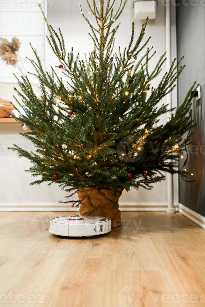 intelligentes Zuhause. Der Roboter-Staubsauger führt eine automatische Reinigung durch. reinigt nach dem Jahreswechsel das Parkett von Christbaumnadeln. reinigt nach den Feiertagen neben dem Weihnachtsbaum. foto