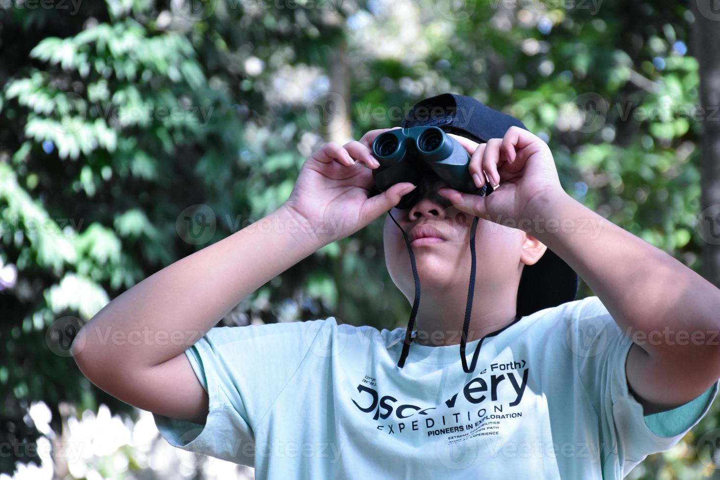 südostasiatische jungen benutzen ferngläser, um vögel im tropischen wald zu beobachten, idee zum lernen von kreaturen und wild lebenden tieren außerhalb des klassenzimmers. foto