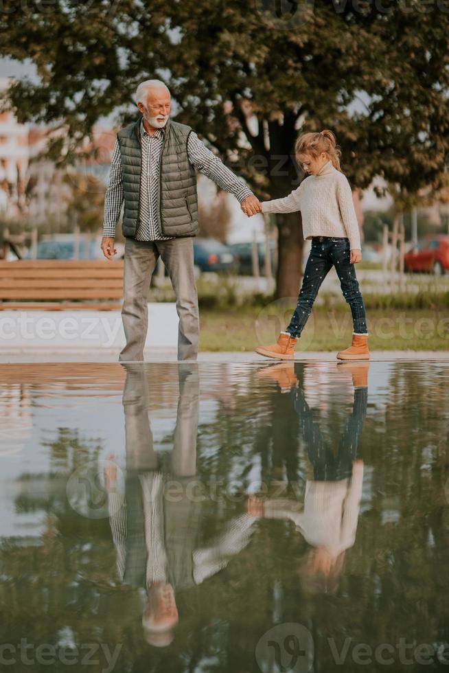Großvater verbringt am Herbsttag Zeit mit seiner Enkelin am kleinen Wasserbecken im Park foto