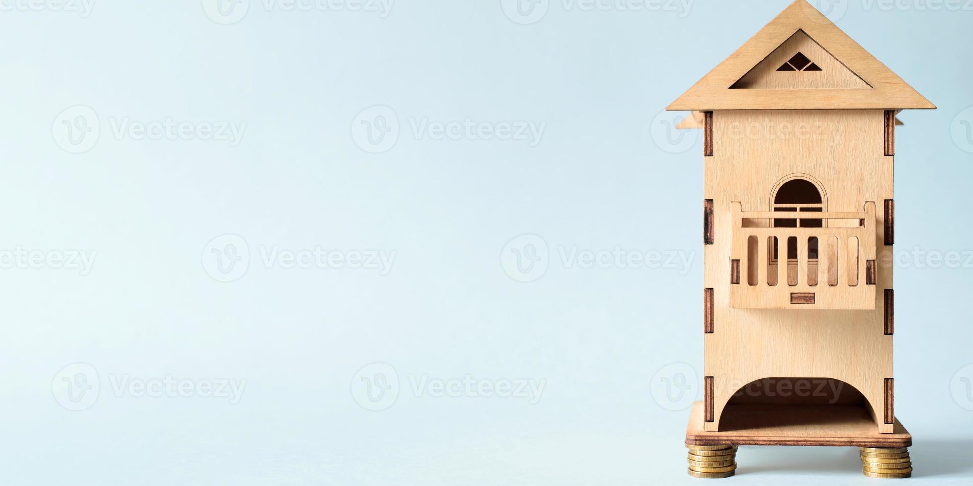 hölzernes miniaturhaus, das auf münzen steht. konzept für die kosten von wohnungen, wohnungsmieten, hypotheken, baugeschäften. Banner, leerer Platz für Text foto