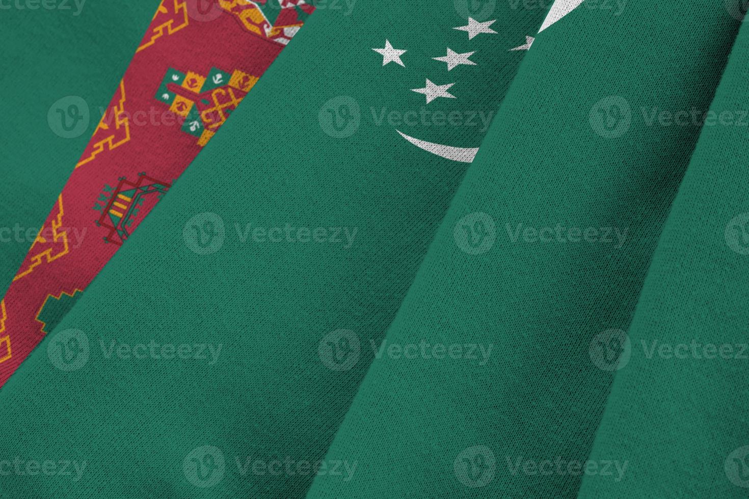 turkmenische flagge mit großen falten, die unter dem studiolicht im innenbereich wehen. die offiziellen symbole und farben im banner foto