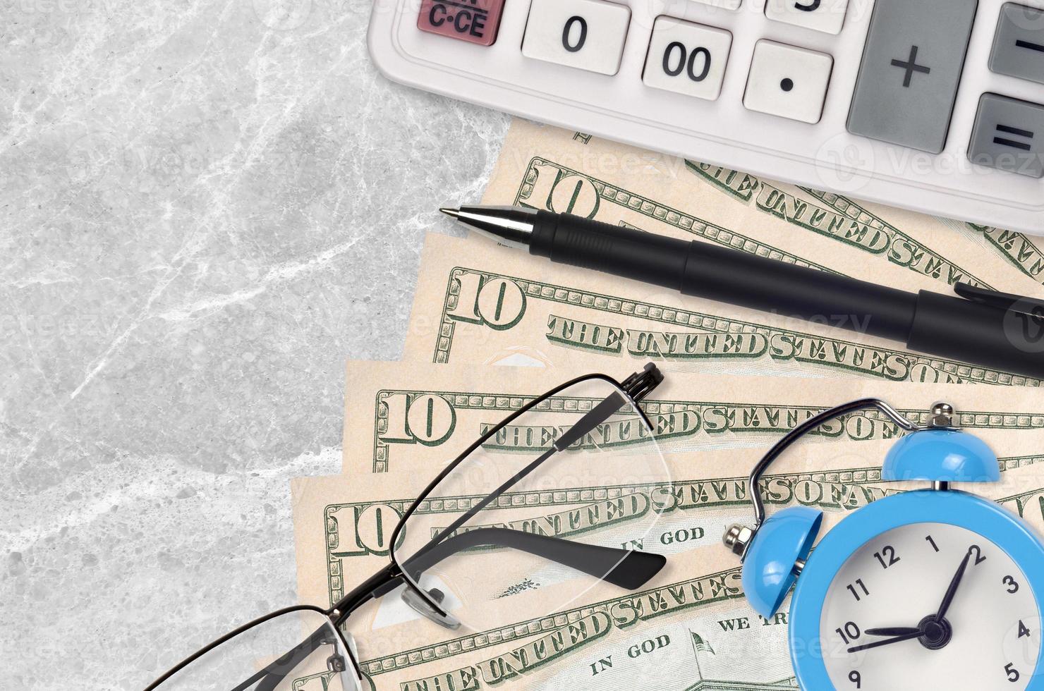 10 US-Dollar-Scheine und Taschenrechner mit Brille und Stift. Konzept für Geschäftsdarlehen oder Steuerzahlungssaison. Zeit, Steuern zu zahlen foto