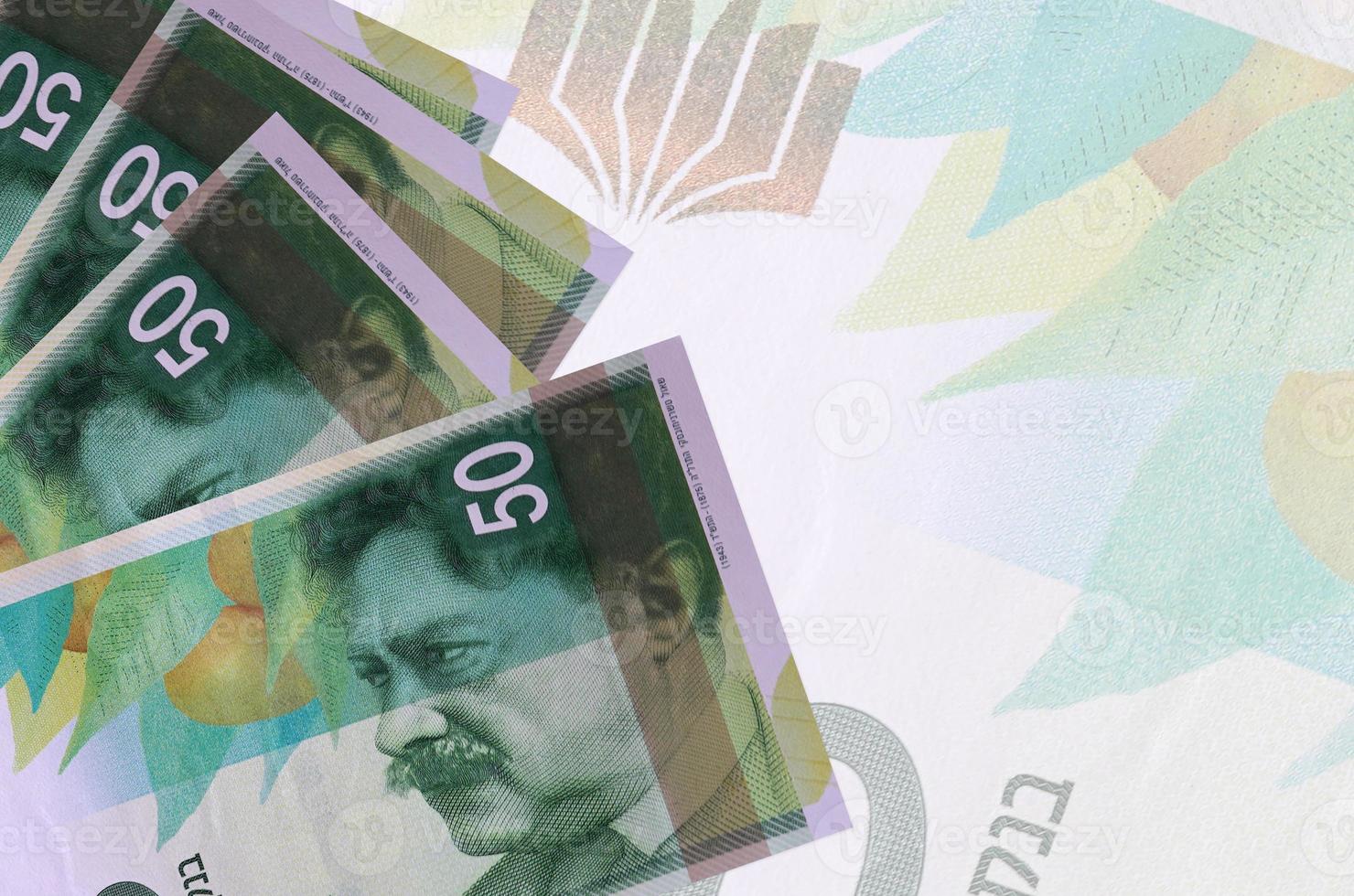 50 israelische neue Schekel-Scheine liegen im Stapel auf dem Hintergrund einer großen halbtransparenten Banknote. abstrakter betriebswirtschaftlicher hintergrund foto