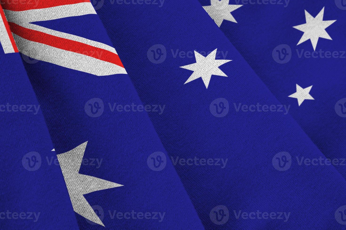 australien-flagge mit großen falten, die nah oben unter dem studiolicht drinnen winken. die offiziellen symbole und farben im banner foto