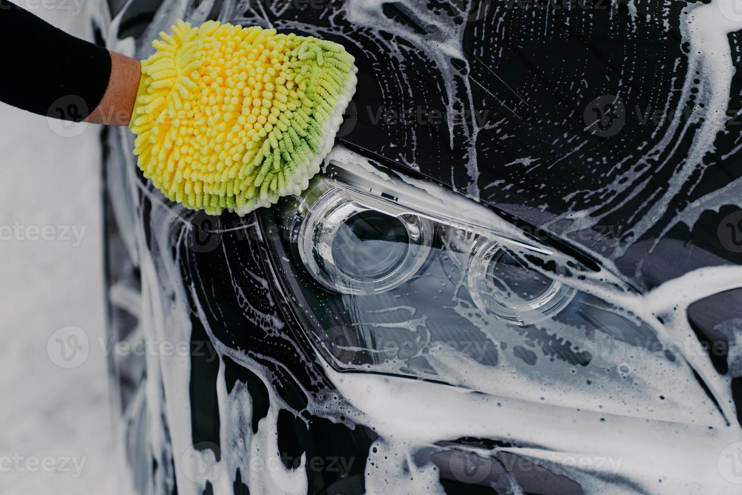 Konzept der menschlichen Handarbeit. mann wäscht auto mit seife und tuch. Fahrzeugreinigung. Nahaufnahme eines Handwischers, der ein Auto wäscht foto