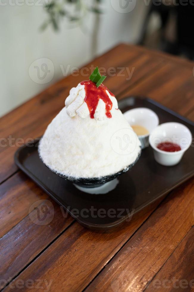 koreanisches rasiertes eisdessert mit süßen belägen, erdbeer-bingsu auf holztisch foto