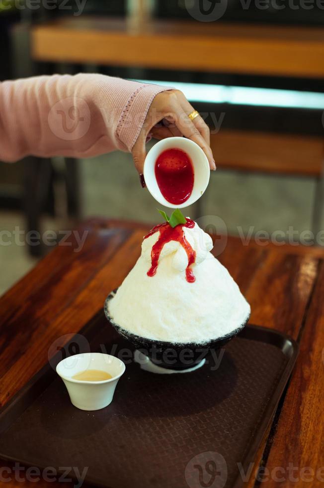 koreanisches rasiertes eisdessert mit süßen belägen, erdbeer-bingsu auf holztisch foto