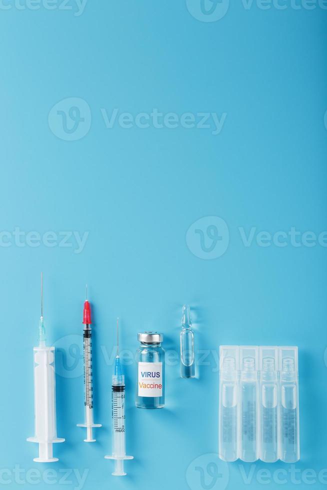 eine Reihe von Ampullen und Spritzen mit der Aufschrift Virusimpfstoff und eine Reihe von Spritzen auf blauem Hintergrund. foto