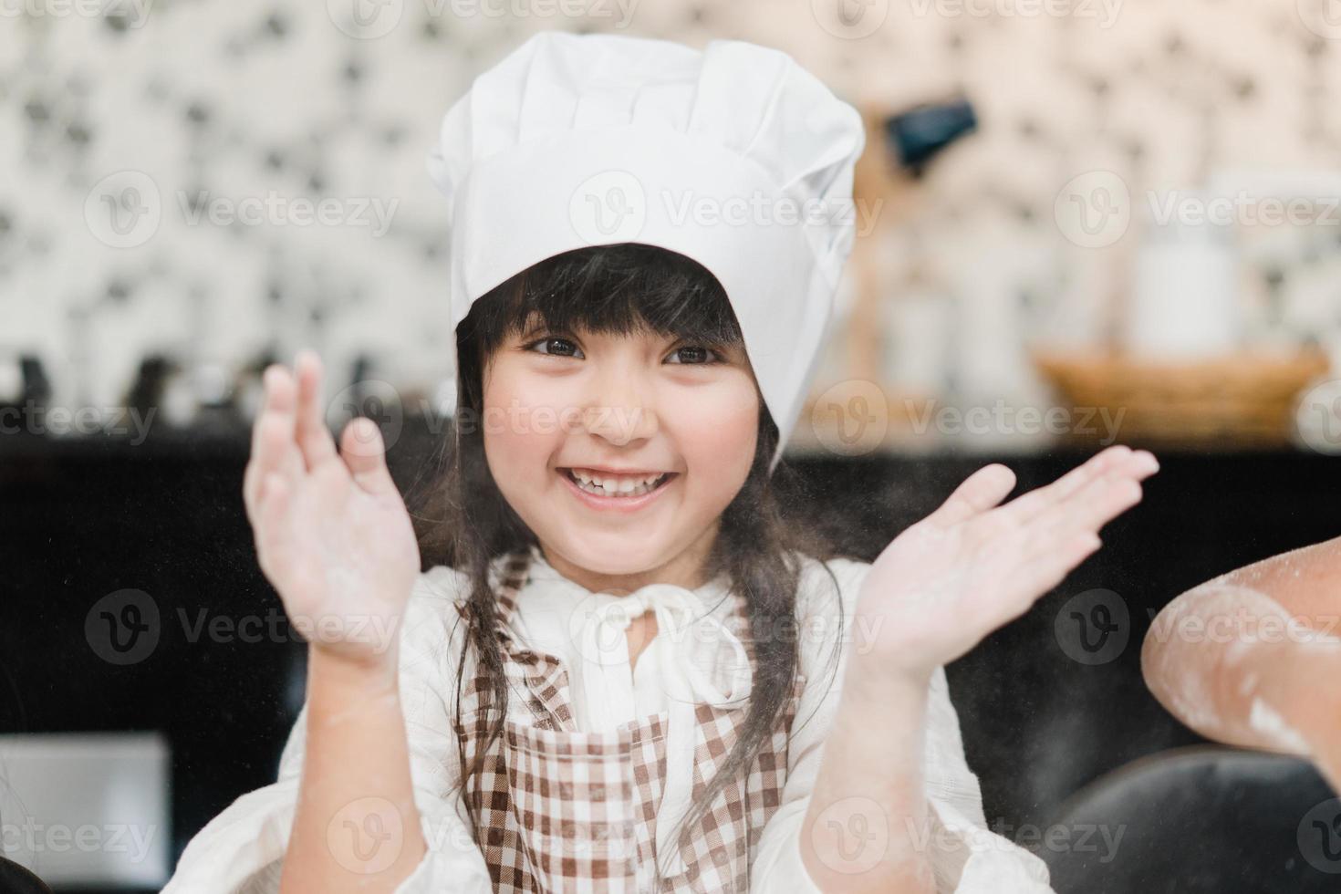 Gruppe von Kindern, die gemeinsam Kuchen im Klassenzimmer backen, multiethnische Jungen und Mädchen, die glücklich sind, Desserts in der Küche in der Schule zu kochen. kinder kochen im schulkonzept. foto