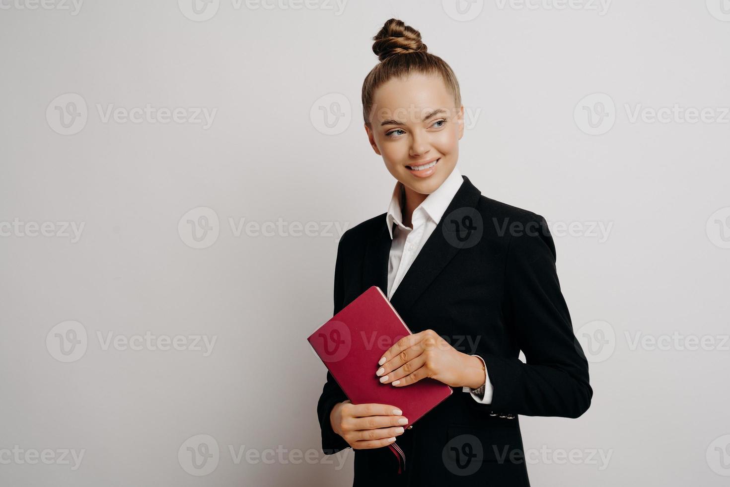 Zufriedene Geschäftsfrau im formellen Outfit mit Notizbuch foto