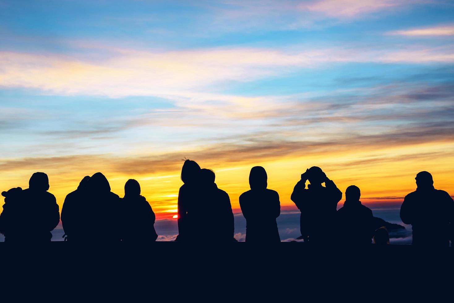 Menschen reisen in die Natur. Reisen entspannen. Hintergrundsilhouette Menschen, die den Sonnenaufgang beobachten und fotografieren foto