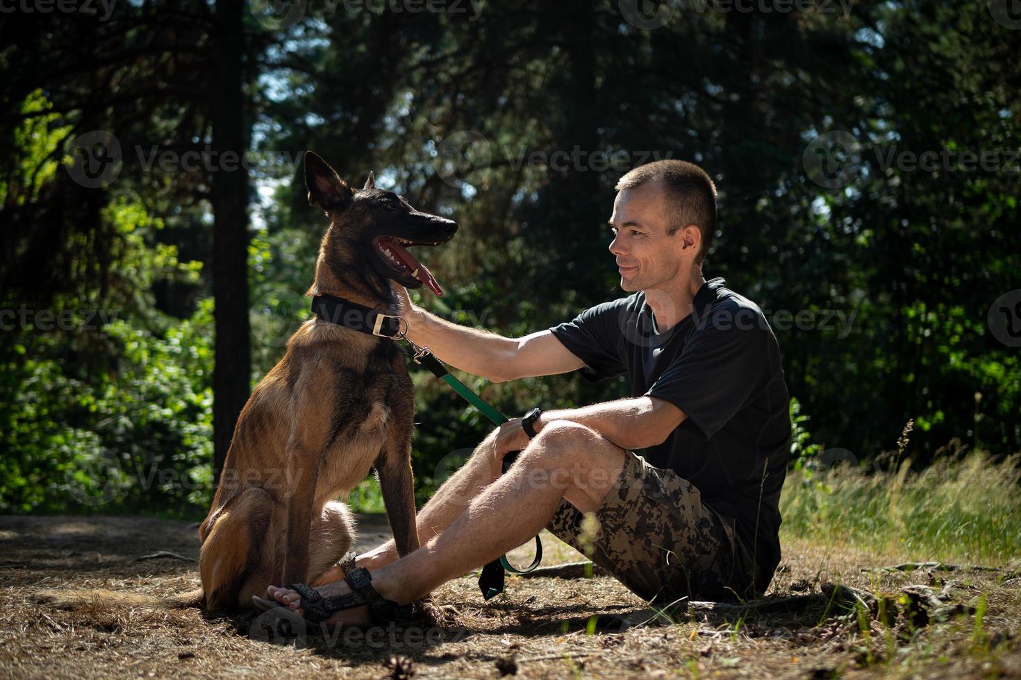 Der junge kaukasische Hipster verbringt an einem sonnigen Sommertag Zeit mit seinem Hund im Park. das Konzept eines Haustieres als Familienmitglied foto