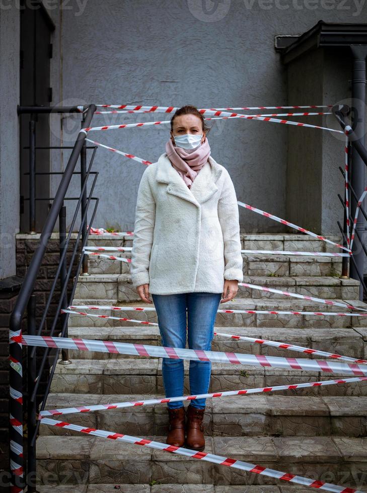 Foto eines Mädchens in einer Maske. mit Warnbändern auf der Straße stehen.