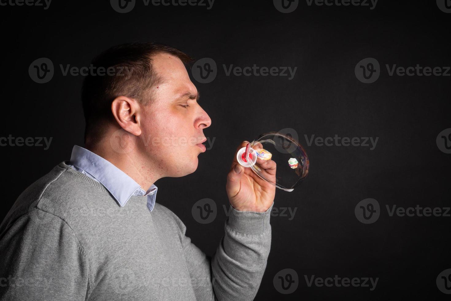 Schöner Mann in einem Anzug bläst Seifenblasen. foto