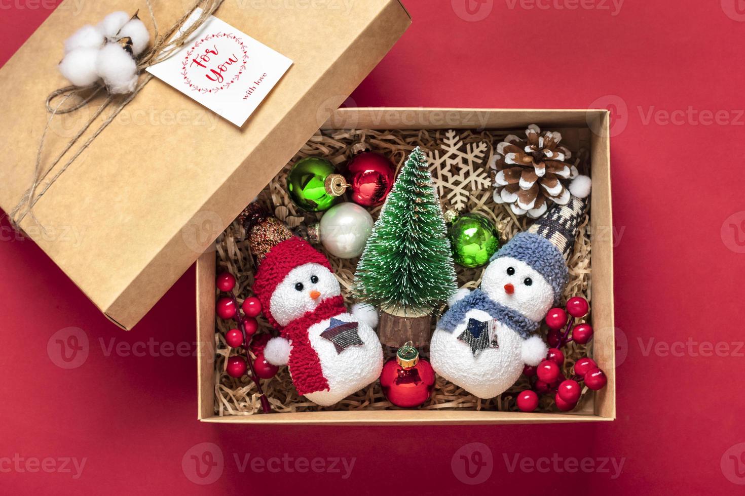 handgemachtes pflegepaket, saisonale geschenkbox mit spielzeug, weihnachtsdekor auf rotem tisch personalisierter umweltfreundlicher korb für familie, freunde, mädchen für den 24. dezember, weihnachten, neujahrstag flach gelegt foto