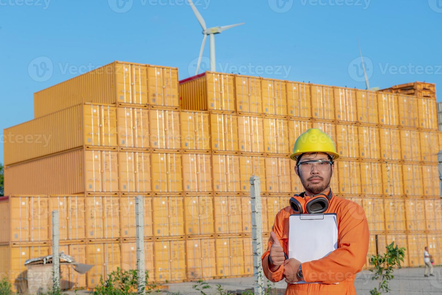 ingenieur, der vor ort arbeitet, um container zu halten, vorarbeiter mit helm, der auf dem containerhof steht und die unversehrtheit des containers überprüft foto