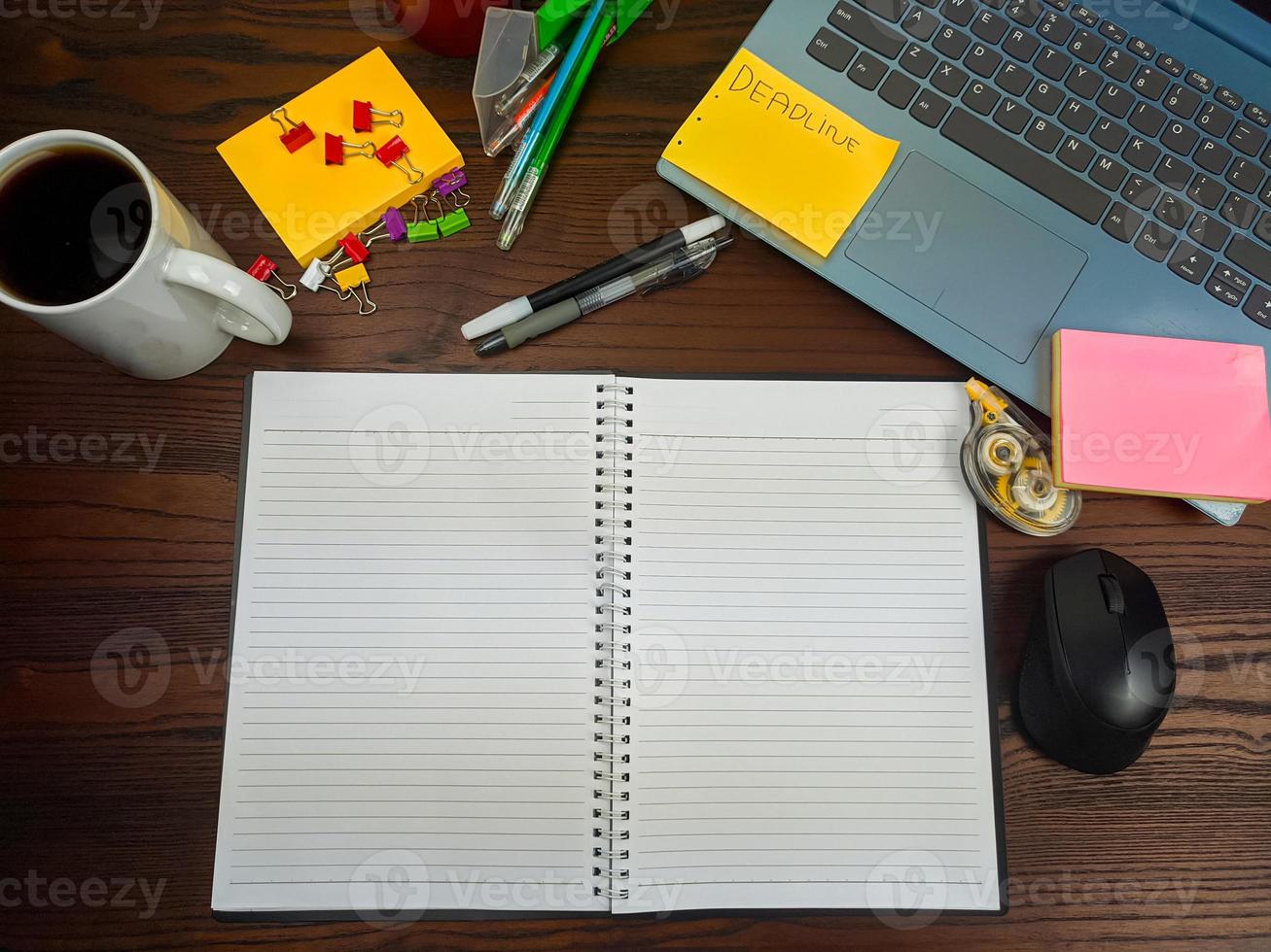 flach gelegt, ein Mock-up eines Notizbuchs. Arbeitsplatz im Hintergrund des Schreibtisches von oben. mit weißen Notizbüchern, Laptops, Büromaterial, Stiften und Kaffeetassen auf dem Holzschreibtisch. foto