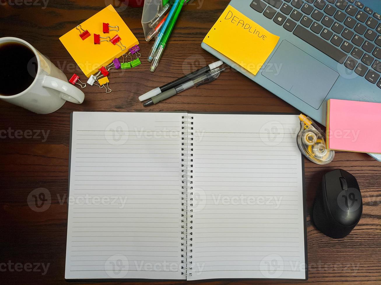 flach gelegt, ein Mock-up eines Notizbuchs. Arbeitsplatz im Hintergrund des Schreibtisches von oben. mit weißen Notizbüchern, Laptops, Büromaterial, Stiften und Kaffeetassen auf dem Holzschreibtisch. foto