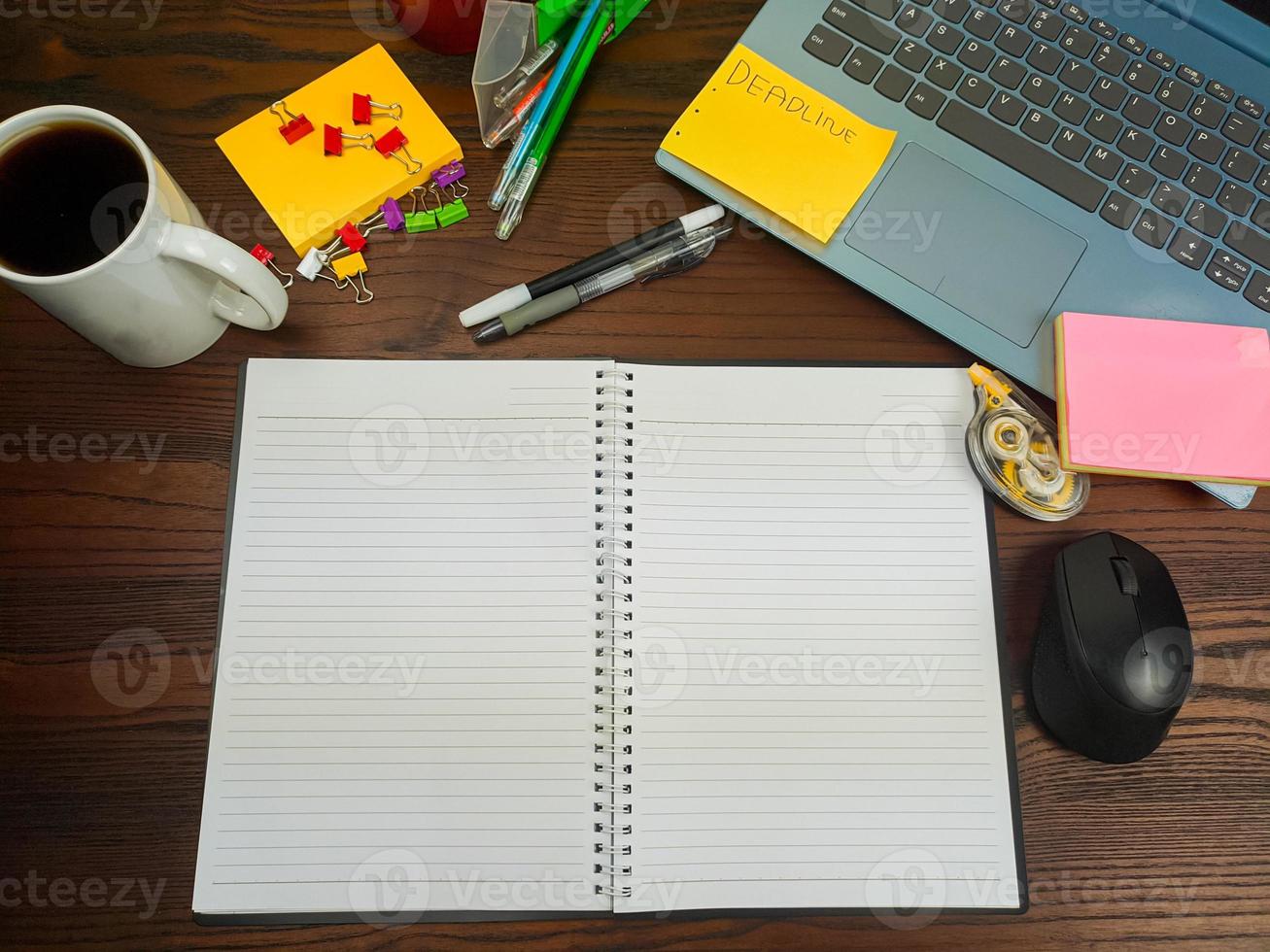 flach gelegt, ein Mock-up eines Notizbuchs. Arbeitsplatz im Hintergrund des Schreibtisches von oben. mit weißen Notizbüchern, Laptops, Büromaterial, Stiften und Kaffeetassen auf dem Holzschreibtisch. foto