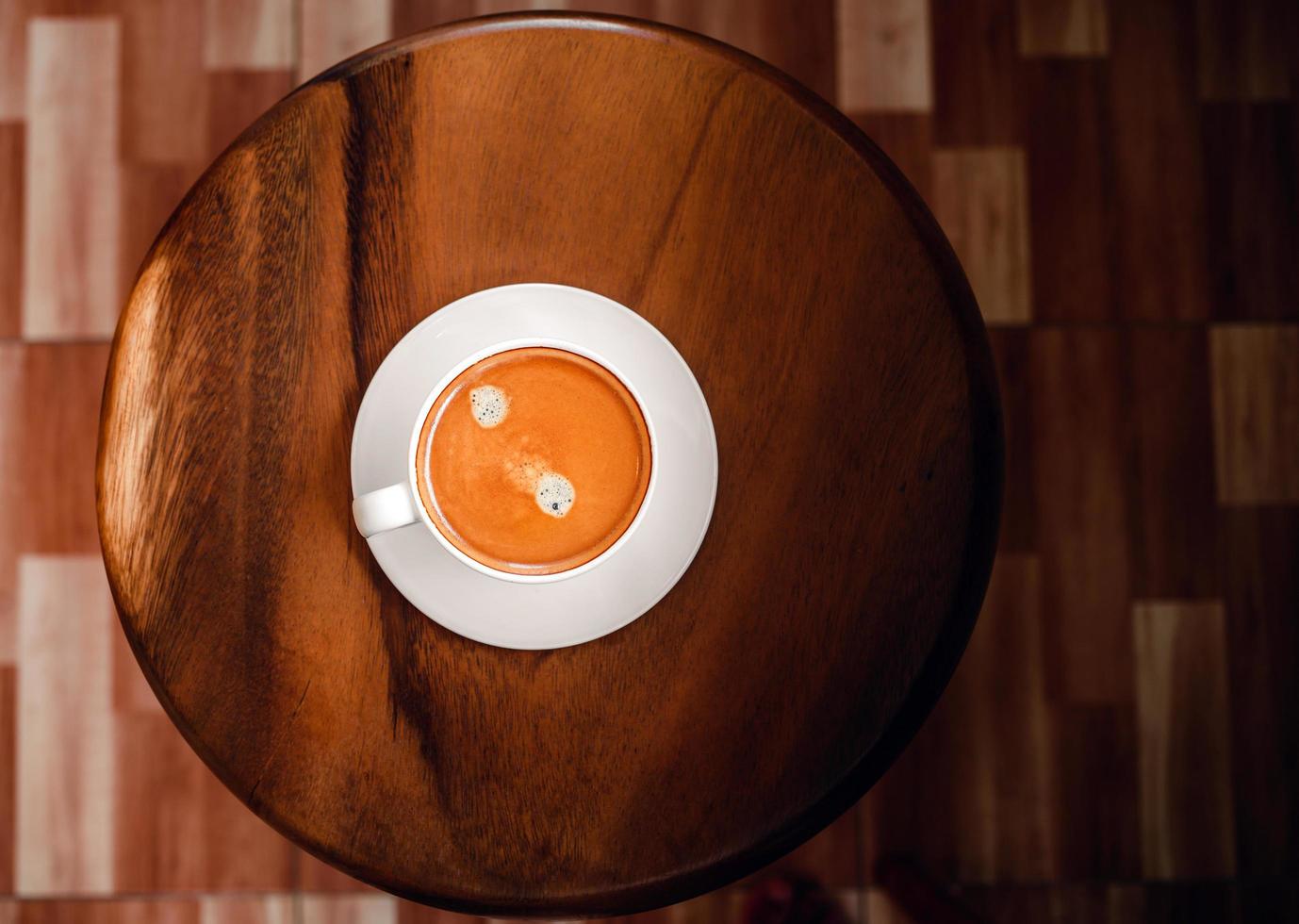 Weiße Tasse Espressokaffee auf einem runden Holzstuhl im Café foto