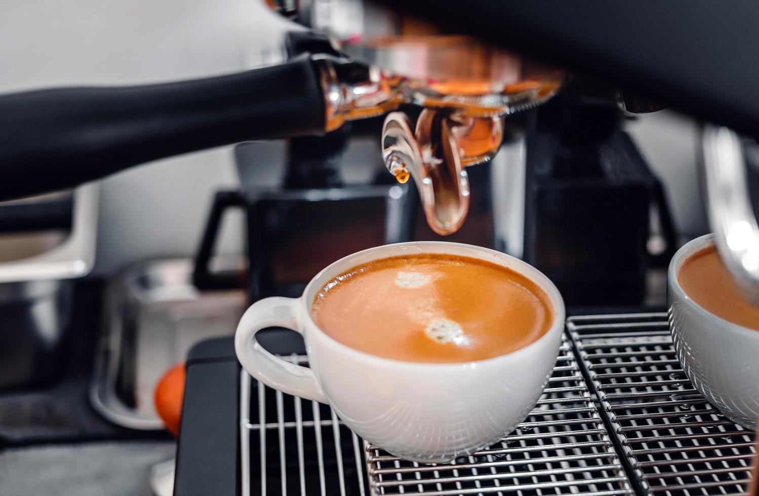 Kaffeeextraktion aus der Kaffeemaschine mit einem Siebträger, der Kaffee in eine Tasse gießt, Espresso aus der Kaffeemaschine im Café foto