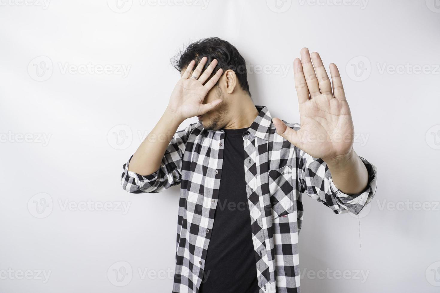 junger verängstigter asiatischer mann isoliert auf weißem hintergrund, sieht deprimiert aus, gesicht bedeckt mit fingern verängstigt und nervös. foto