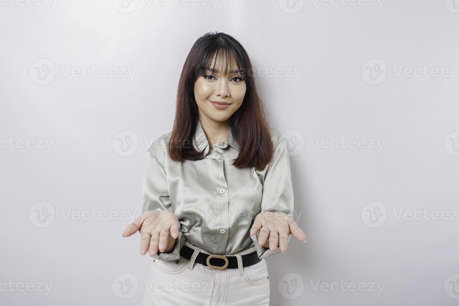 Junge asiatische Frau mit salbeigrünem Hemd, die eine Idee präsentiert, während sie auf isoliertem weißem Hintergrund lächelt foto