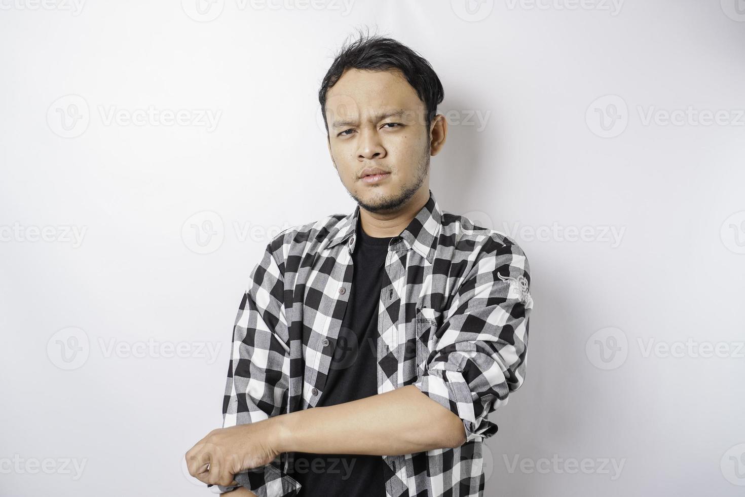 Porträt eines selbstbewussten lächelnden asiatischen Mannes mit Tartanhemd, der mit verschränkten Armen steht und isoliert auf weißem Hintergrund in die Kamera schaut foto