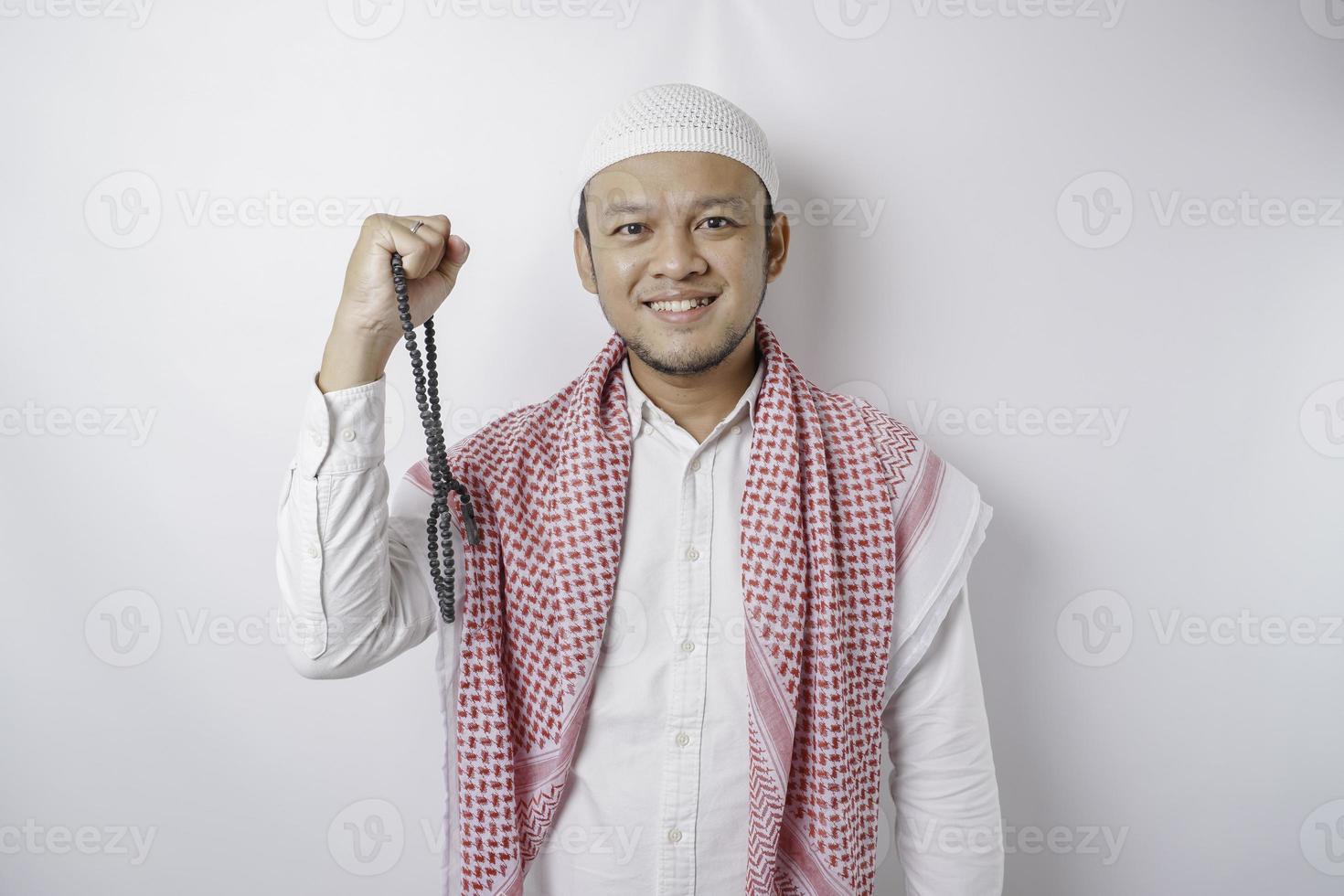 ein junger asiatischer muslimischer mann mit einem glücklichen erfolgreichen ausdruck, der durch weißen hintergrund isoliert wird foto