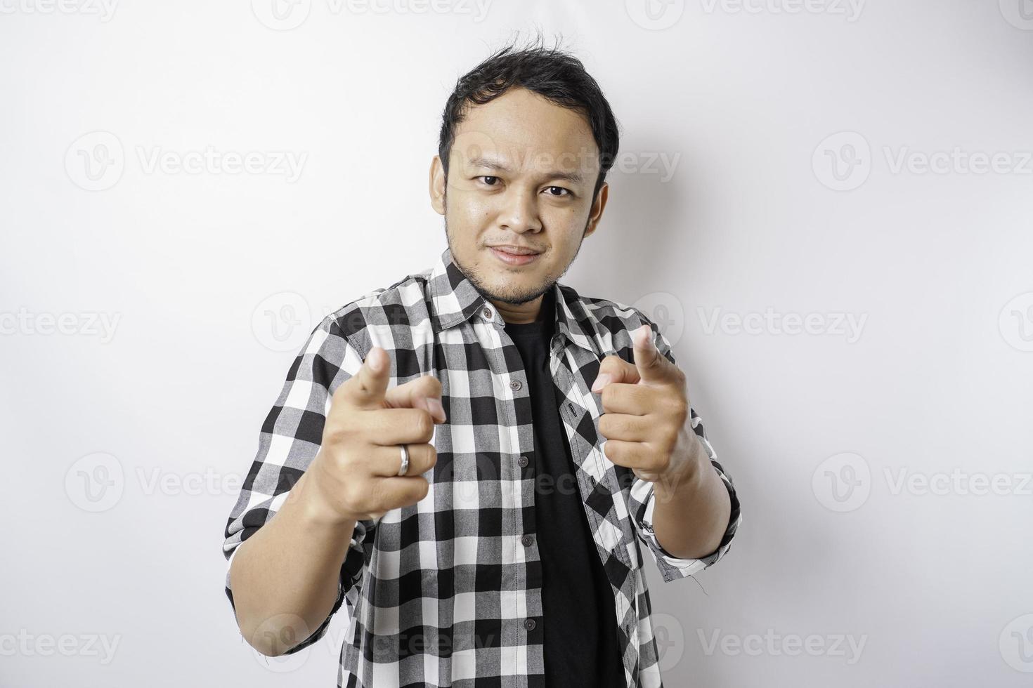 Junger asiatischer Mann mit Tartanhemd, der vor isoliertem weißem Hintergrund steht und mit glücklichem Gesicht mit dem Finger auf die Kamera zeigt. gute Energie und Stimmung. foto