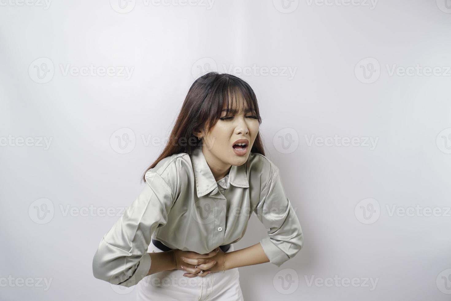 Foto einer jungen unwohl kranken kranken Frau, die die Hand auf dem Bauch hält, leidet Schmerzen isoliert auf weißem Hintergrund